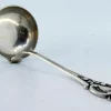 Silberne Suppenkelle mit Griffrillen und Monogrammkarte