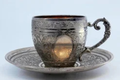 Tasse und Untertasse aus Neusilber mit gravierten Blumenmotiven und Monogrammkarte, 2 . Set